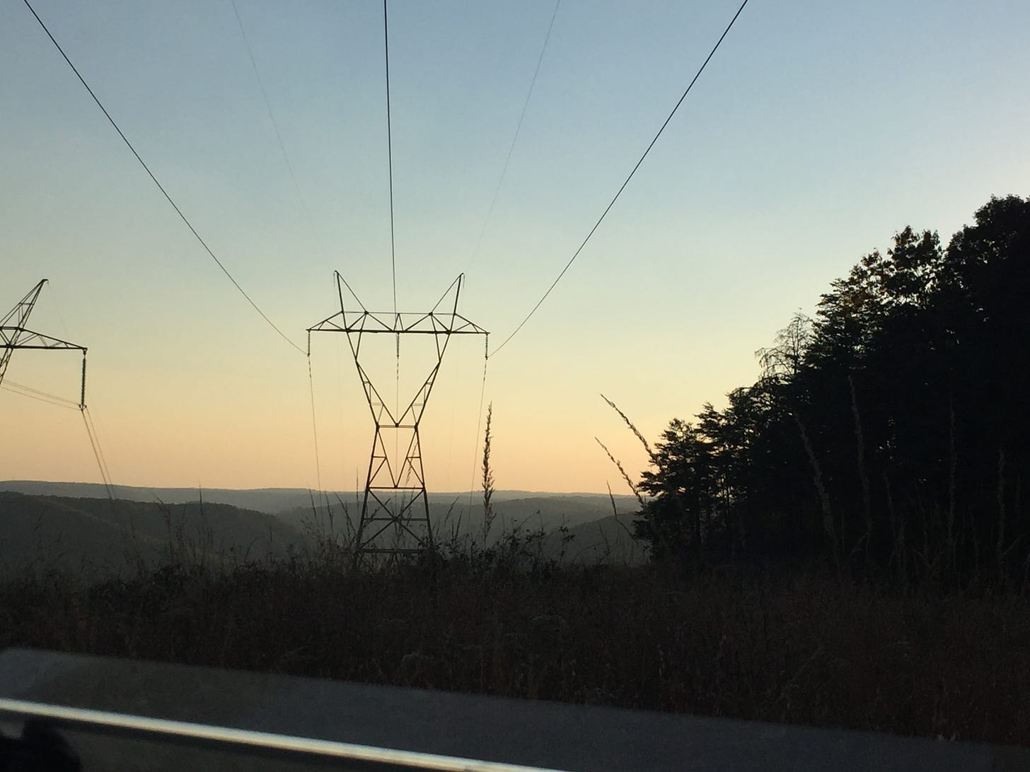 photo of mountains in the distance, with large power transmission lines/poles in the center of the image