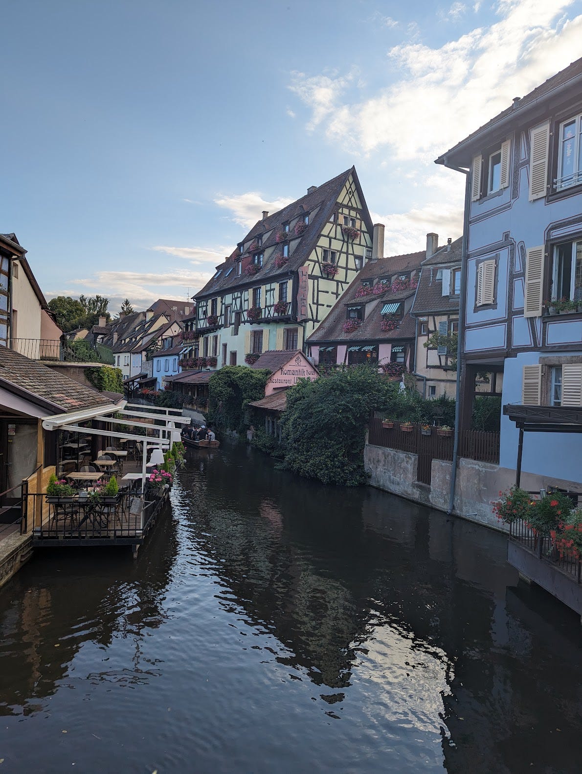 A view of "Little Venice" in Colmar. A canal is flanked by half-timber houses in pastel colors. The scene is picturesque.