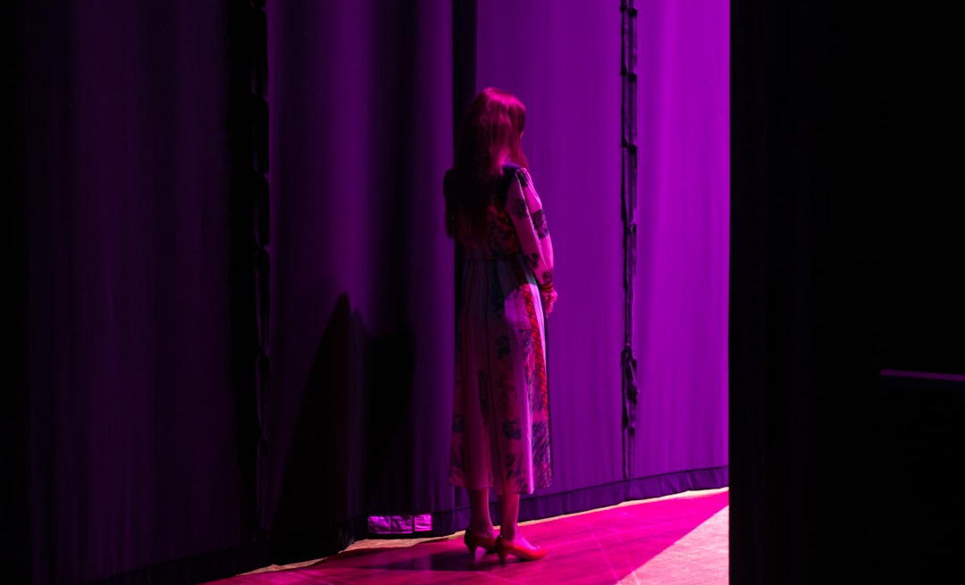 a woman standing in front of a purple curtain