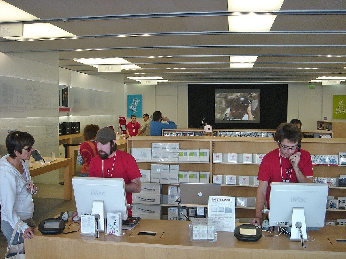 Employees at Apple Pasadena assist customers at a counter with iMac G5s.
