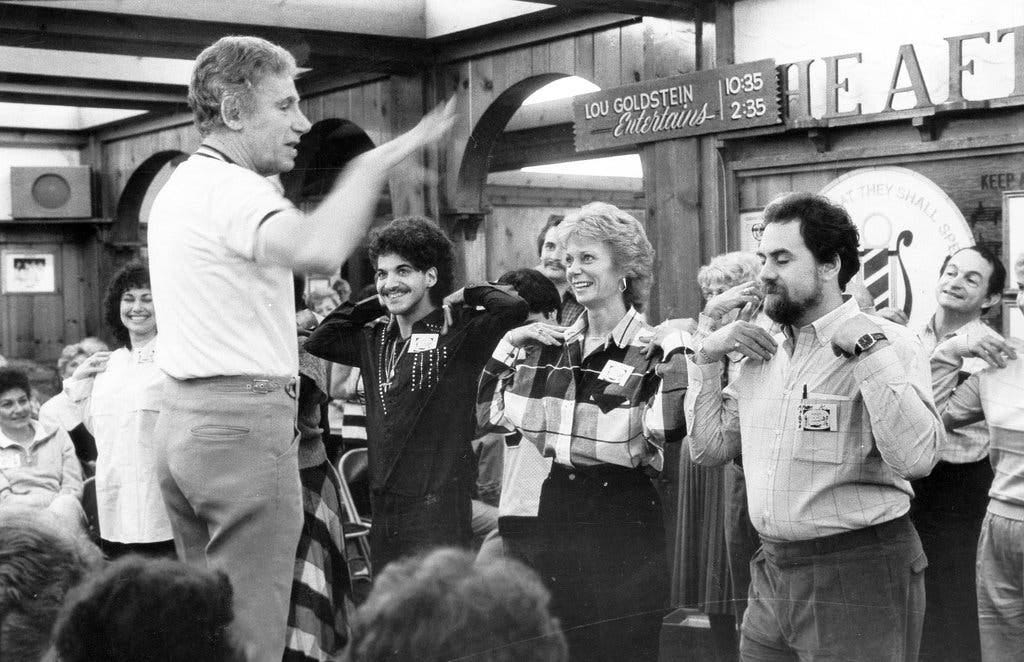 Lou Goldstein, left, leading a game of Simon Says at Grossinger&#8217;s in 1985. He worked at Grossinger&#8217;s from 1948 until it closed in 1986 as a tummler, keeping hotel guests amused.