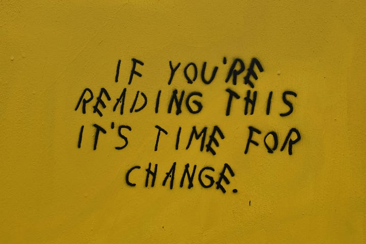 Black grafitti on a yellow wall that reads “If you’re reading this, it’s time for change.”