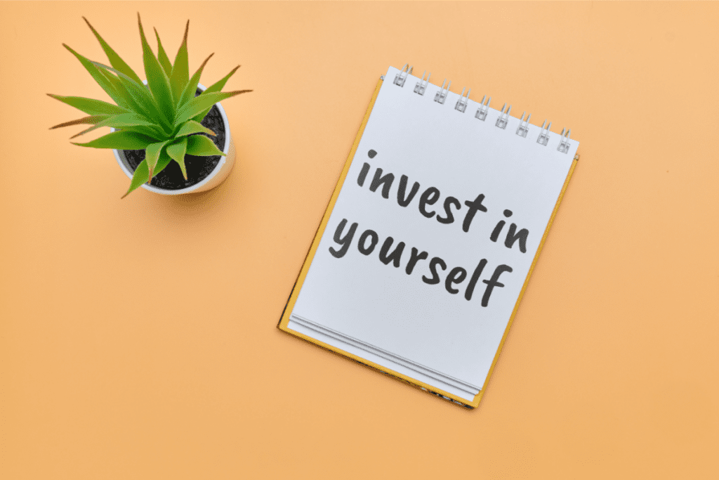 concept invest in yourself notepad inscription on an orange table