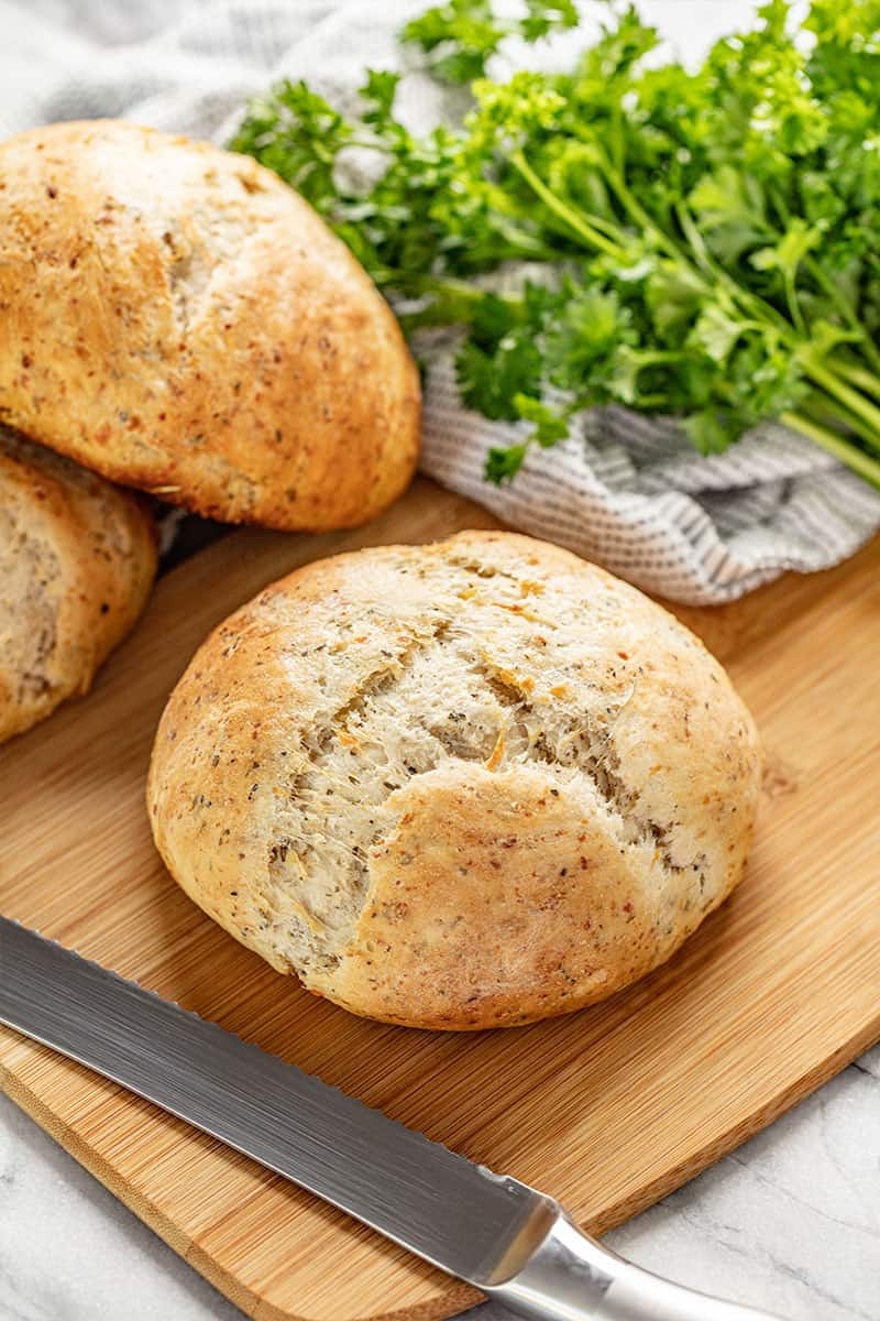 Rustic Garlic Parmesan Herb Bread on a cutting board with a bread knife by it.