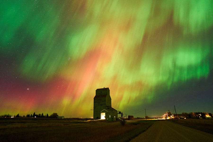 The northern lights illuminate the sky over an old grain elevator.