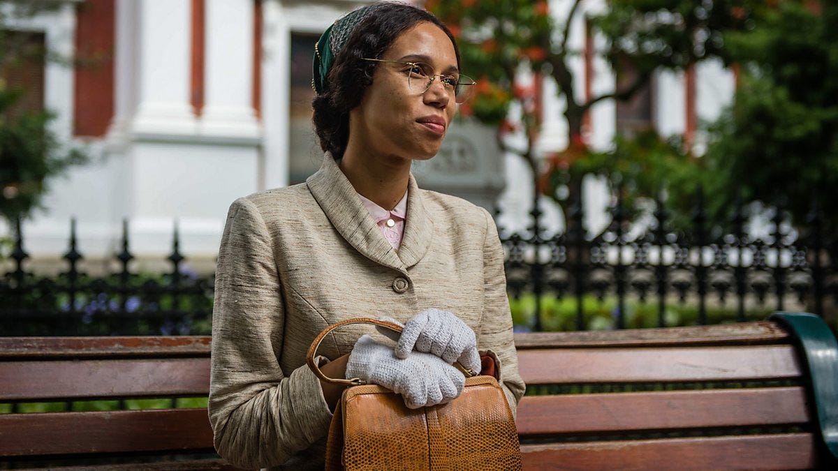This image shows Rosa Parks (played by Vinette Robinson) sitting on a bench while awaiting a bus in 1955 Montgomery, Alabama. Parks holds her purse on her lap. This image shows Rosa Parks (played by Vinette Robinson) sitting on a bench while awaiting a bus in 1955 Montgomery, Alabama. Parks holds her purse on her lap.