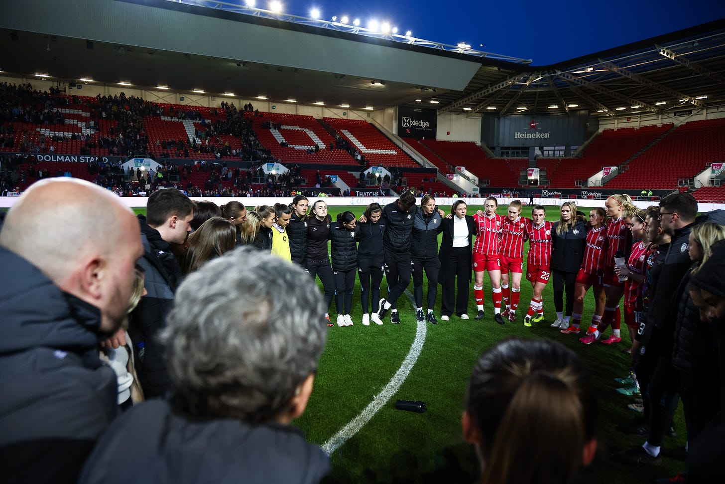 The Bristol City players and staff huddle on the pitch after relegation.