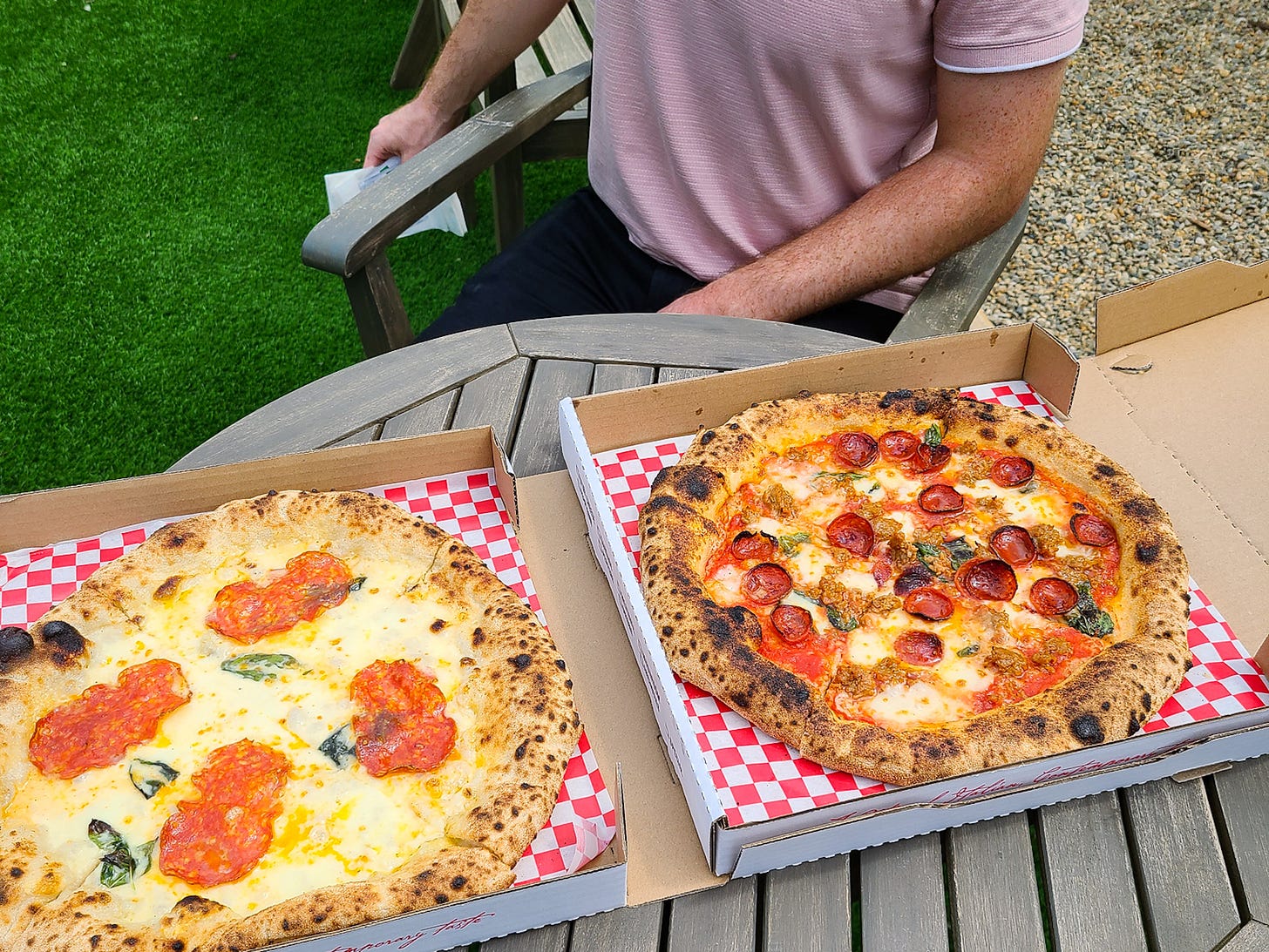 two Neapolitan pizzas freshly baked in their boxes on a table ready to be devoured