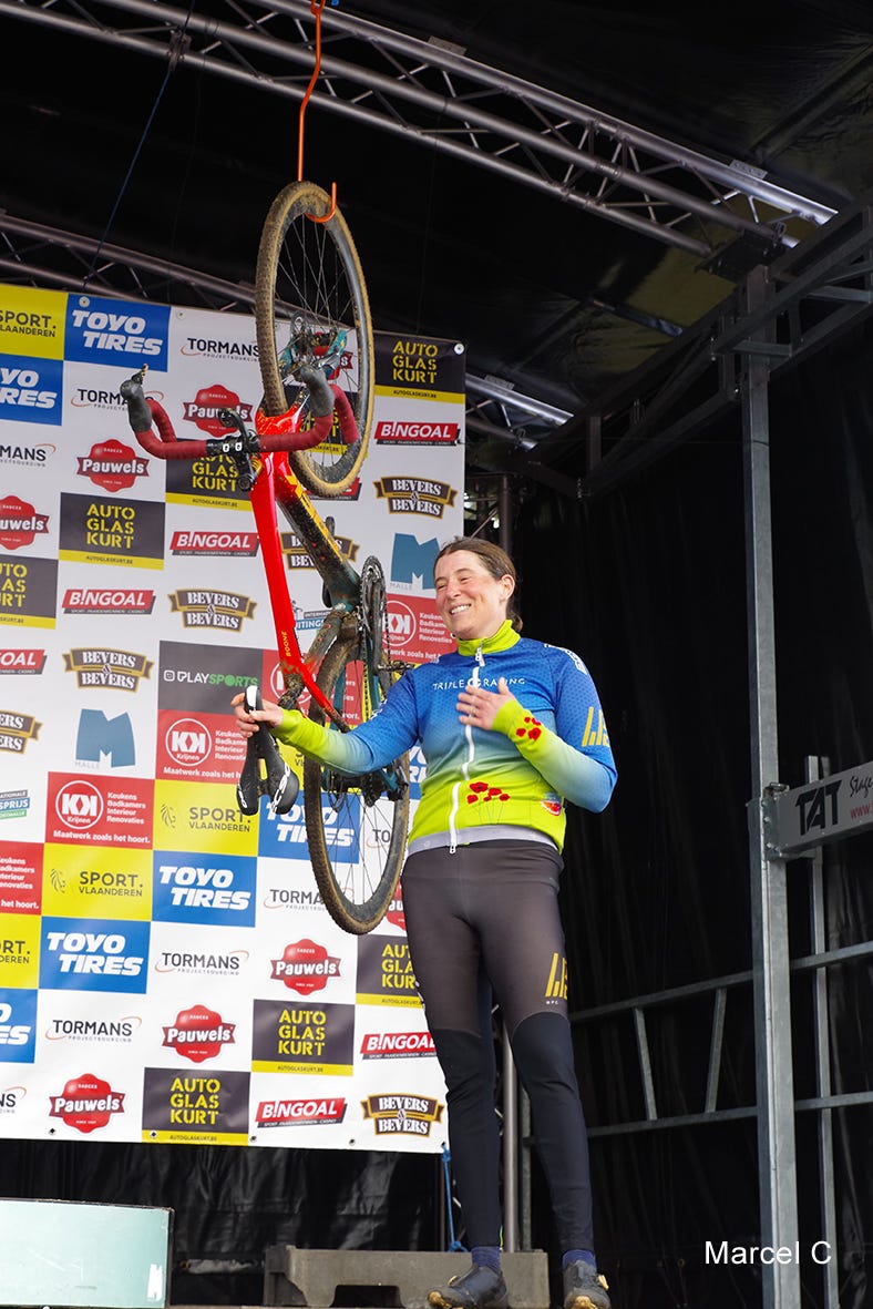 Female cyclist Corey Coogan Cisek lifts her bike onto the Oostmalle hook as she retires from professional cyclocross racing