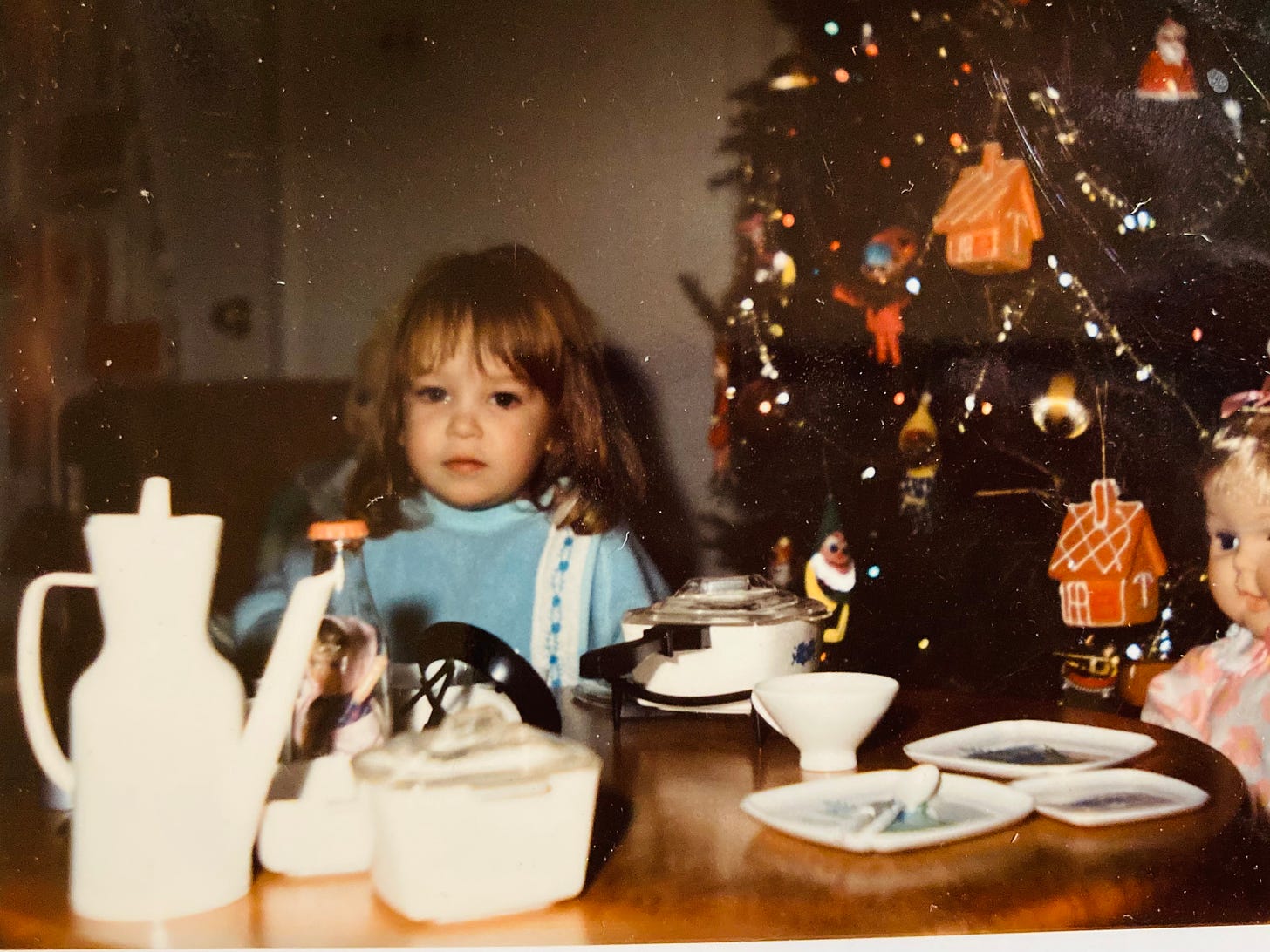 Little girl and doll having tea party by the Christmas tree