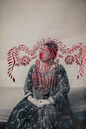A woman in a long dress with swirls and floral flourishes of red paper cuts obscuring her face