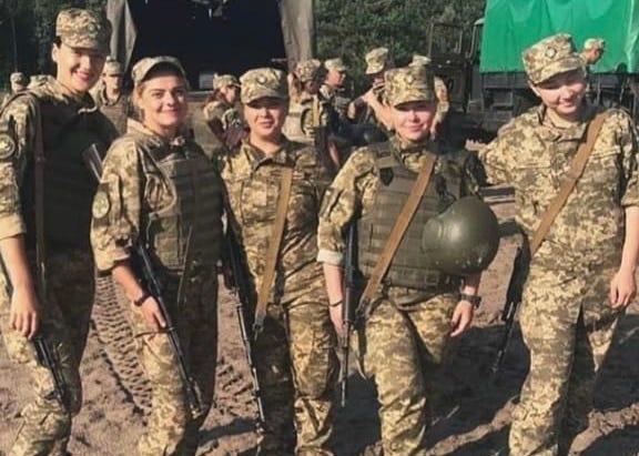 Anna and other women soldiers in uniform and bullet-proof vests next to each other.