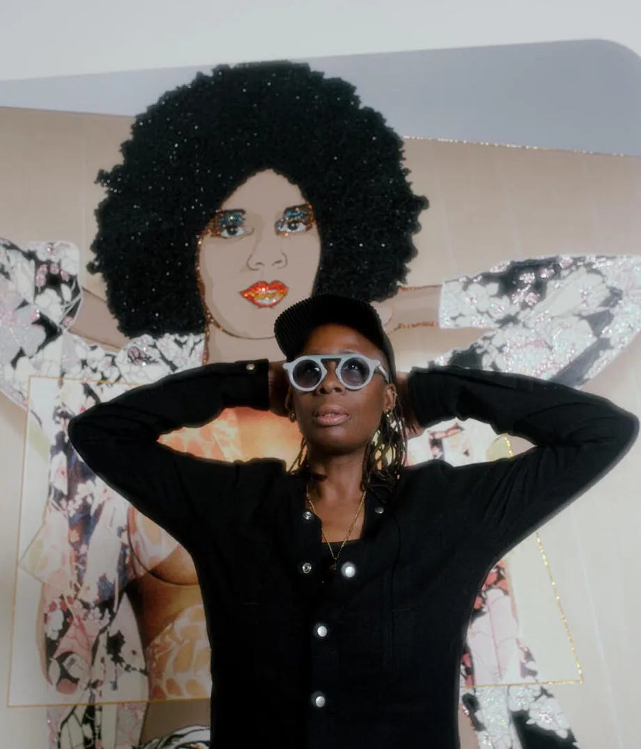 Mickalene standing with her hands behind her head, posing in front of her Maya Portrait #10, which is posed the same way. Mickalene is a black women, wearing a black sweater, and she has on a black baseball cap, and gray geometric glasses Mickalene standing with her hands behind her head, posing in front of her Maya Portrait #10, which is posed the same way. Mickalene is a black women, wearing a black sweater, and she has on a black baseball cap, and gray geometric glasses
