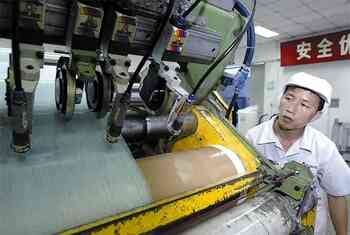 A Chinese factory worker stands by a machine.
