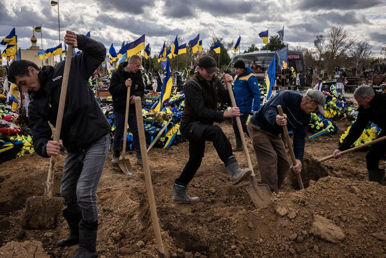 Men dig to fill the graves of two soldiers during their joint funeral in a cemetery on the outskirts of Kherson, Ukraine, in November. (Ed Ram for The Washington Post/FTWP)
