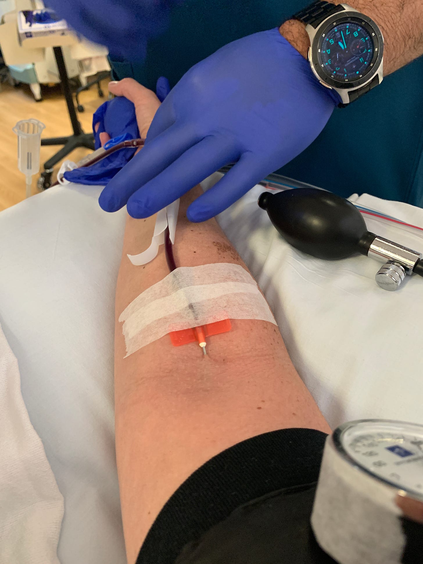 an outstretched arm with a needle inserted into a vein giving blood.
