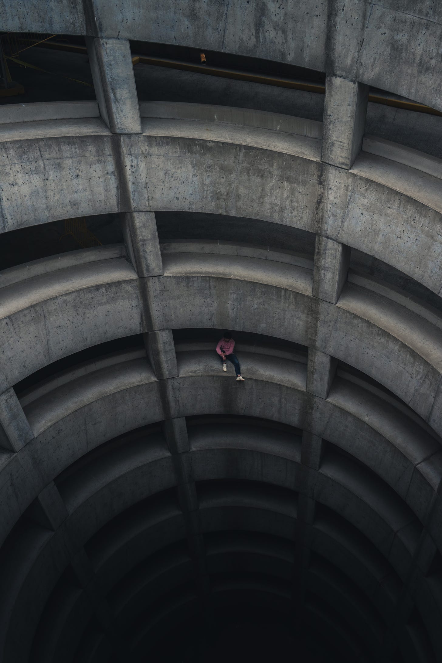 concrete spiral parking ramp with man sitting mid-level