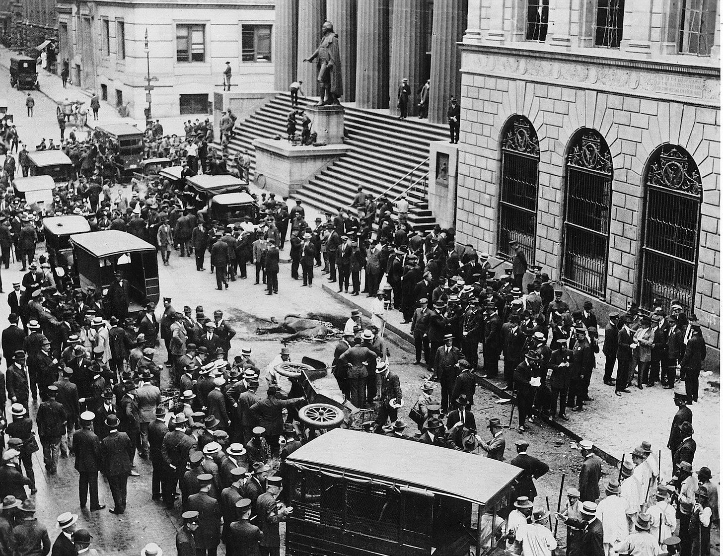 Wall Street bombing of 1920. Hundreds of people looking at an overturned car a dead horse and other debris from the bombing. 