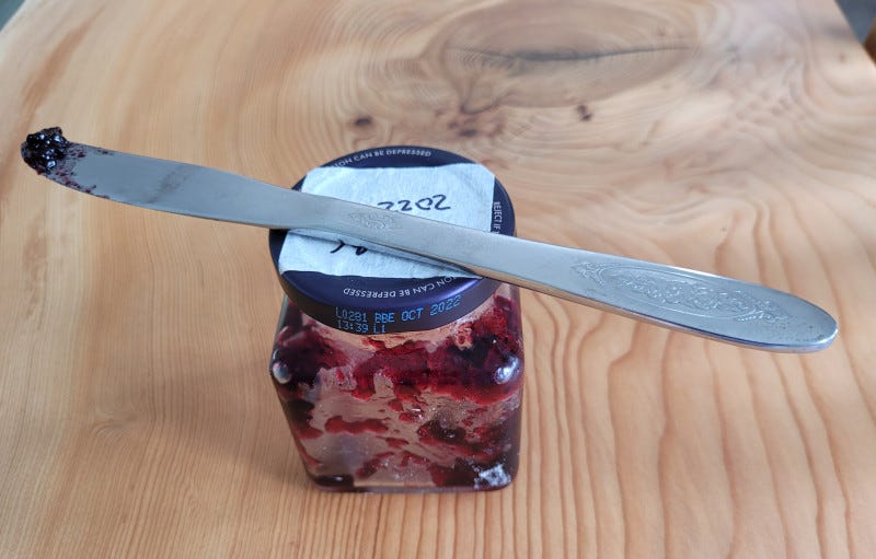 Sticky knife on top of jam jar. 