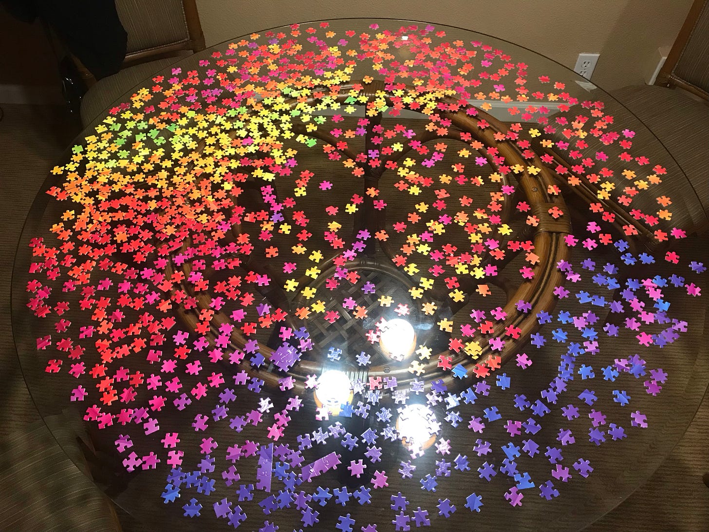 Yellow, red, pink, purple and blue puzzle pieces on a glass table