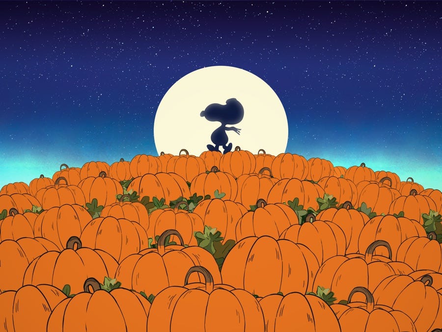 Snoppy is silhouetted against an enormous harvest moon. He is walking across a giant heap of bright orange halloween pumpkins that have just been harvested. The night sky is dark blue and filled with galaxies of stars