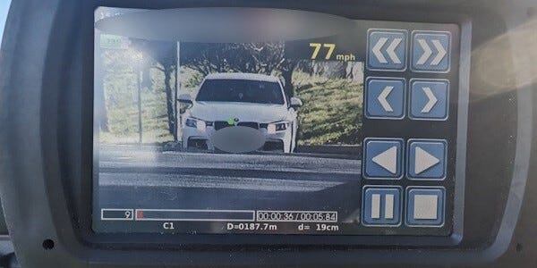Speed check device showing a white car travelling at 77 miles per hour