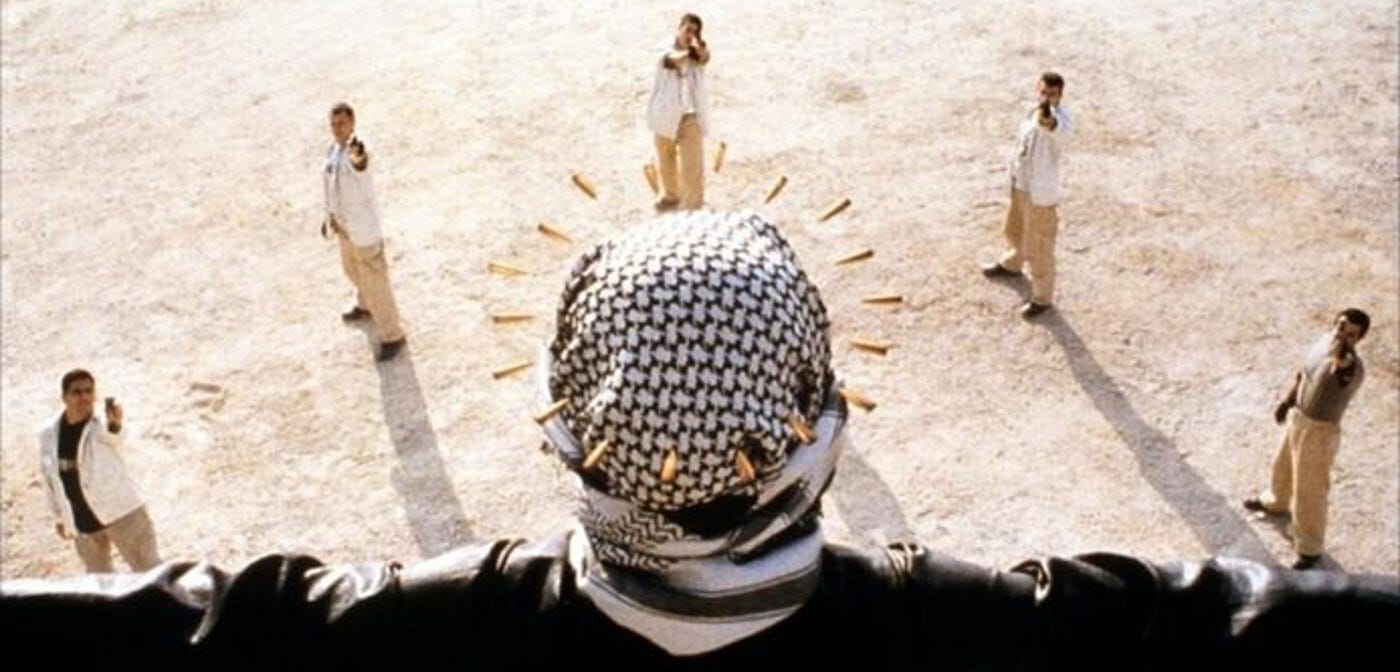 A shot from Divine Intervention of the back of a woman's head as she wears a kuffiyeh. Five Israeli soldiers point guns at her from below and the bullets for a halo around her head.