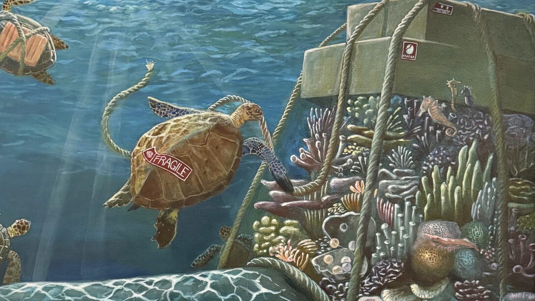 A painting shows a turtle with a packaging label that says FRAGILE near a coral reef covered with rope and packages also labeled FRAGILE.