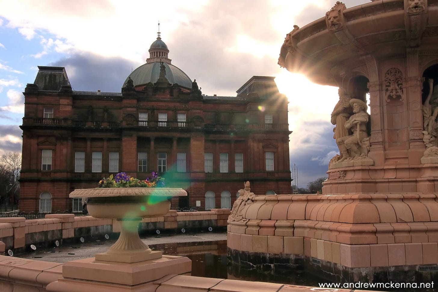 The People's Palace and the Doulton Fountain with the sun casting a lens flare across the frame from right to left.