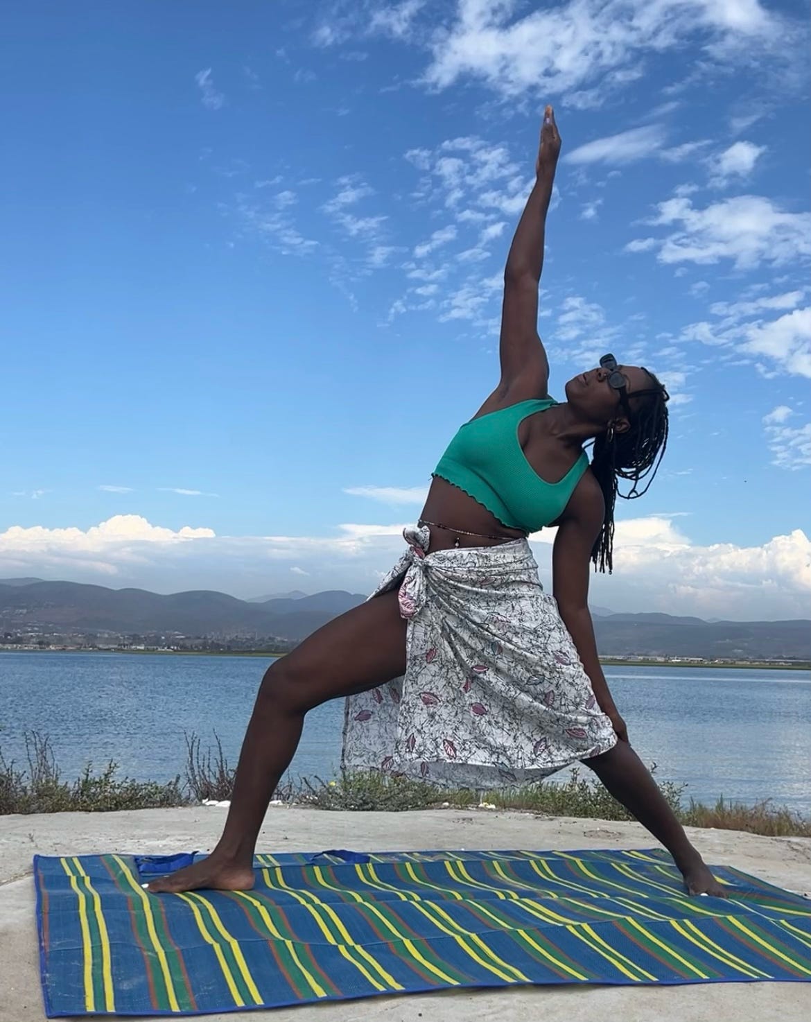 Peaceful warrior pose with black woman by ocean