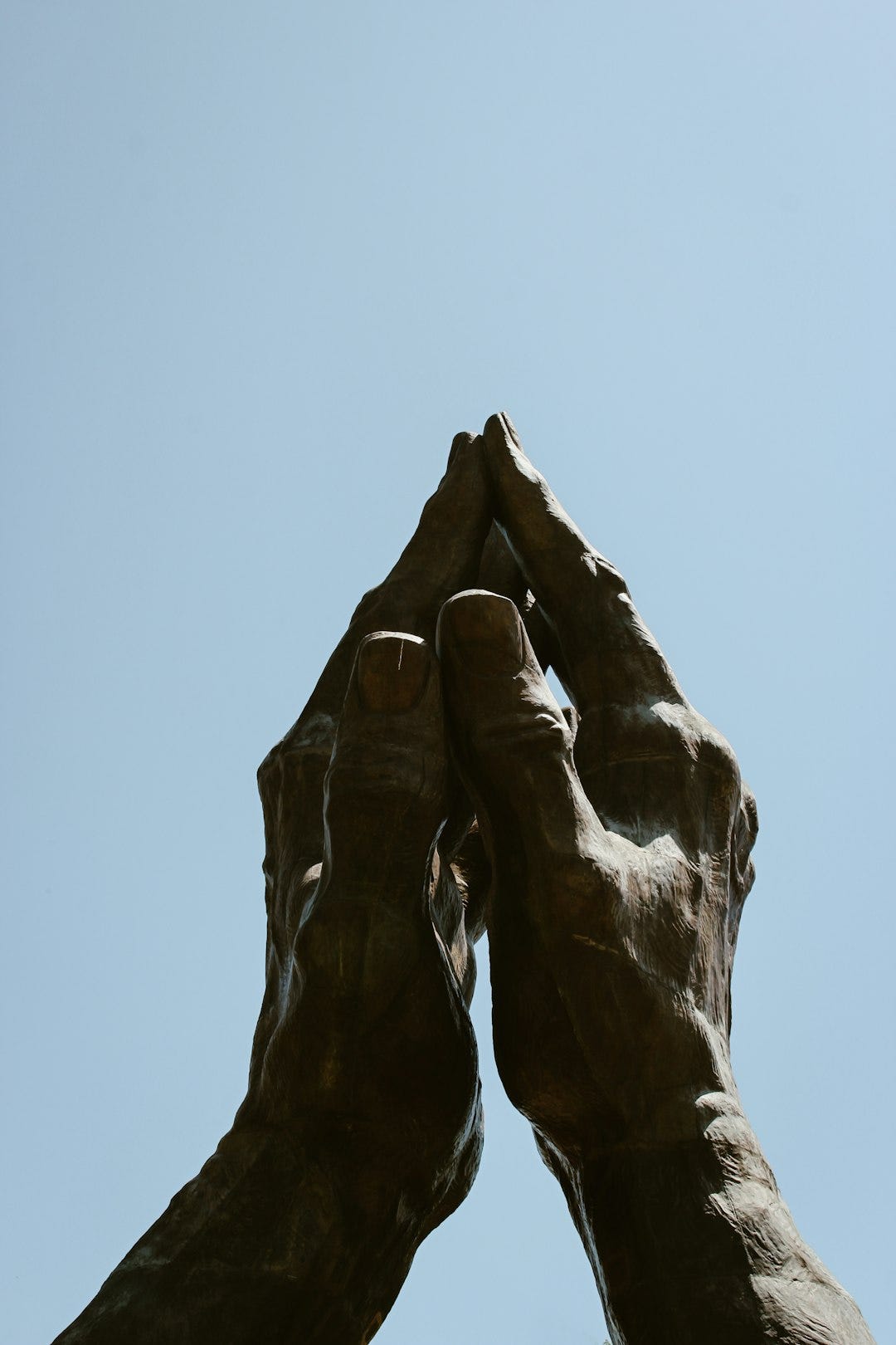 a statue of two hands reaching up into the sky