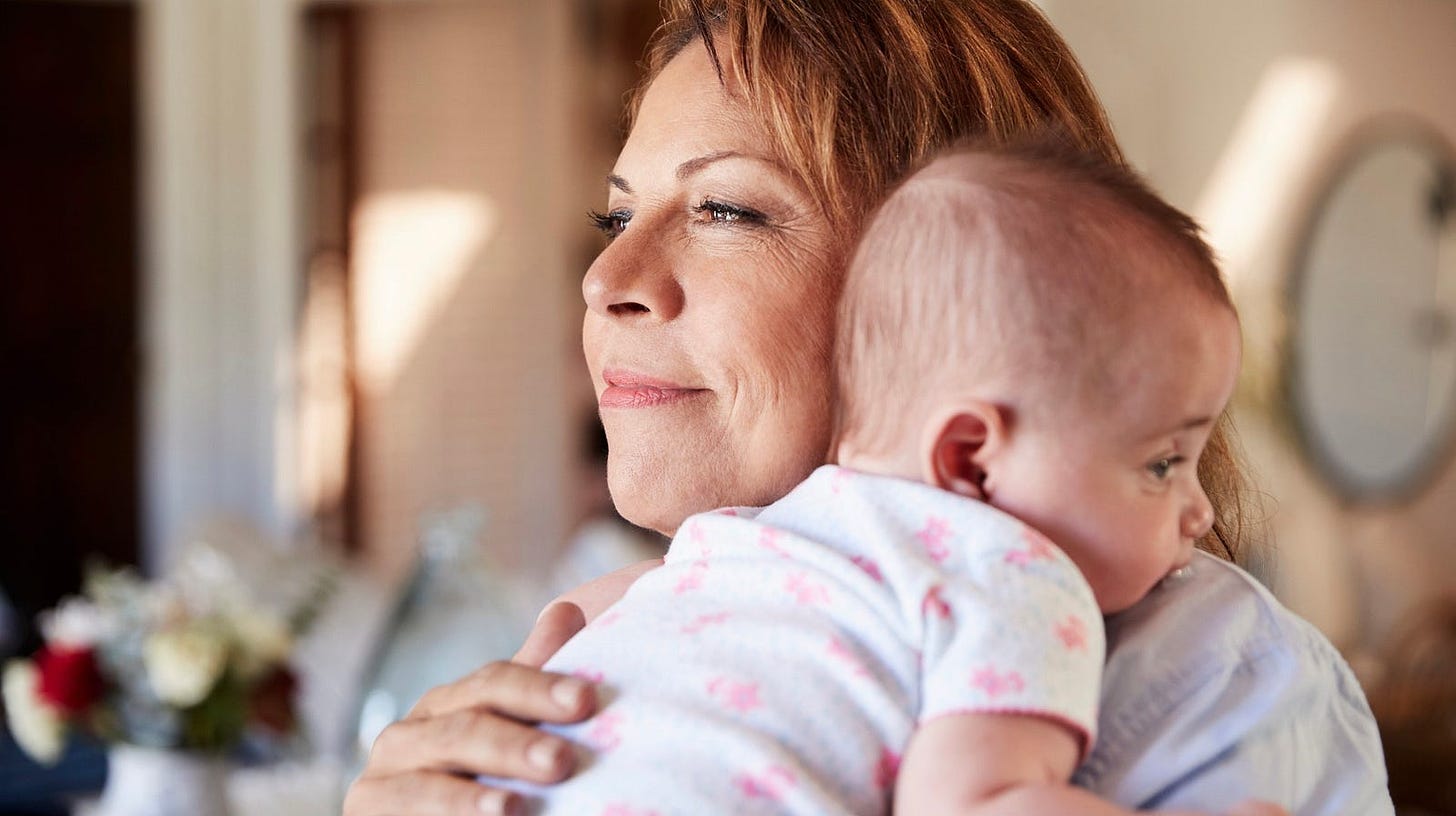 A middle aged woman holds a baby.