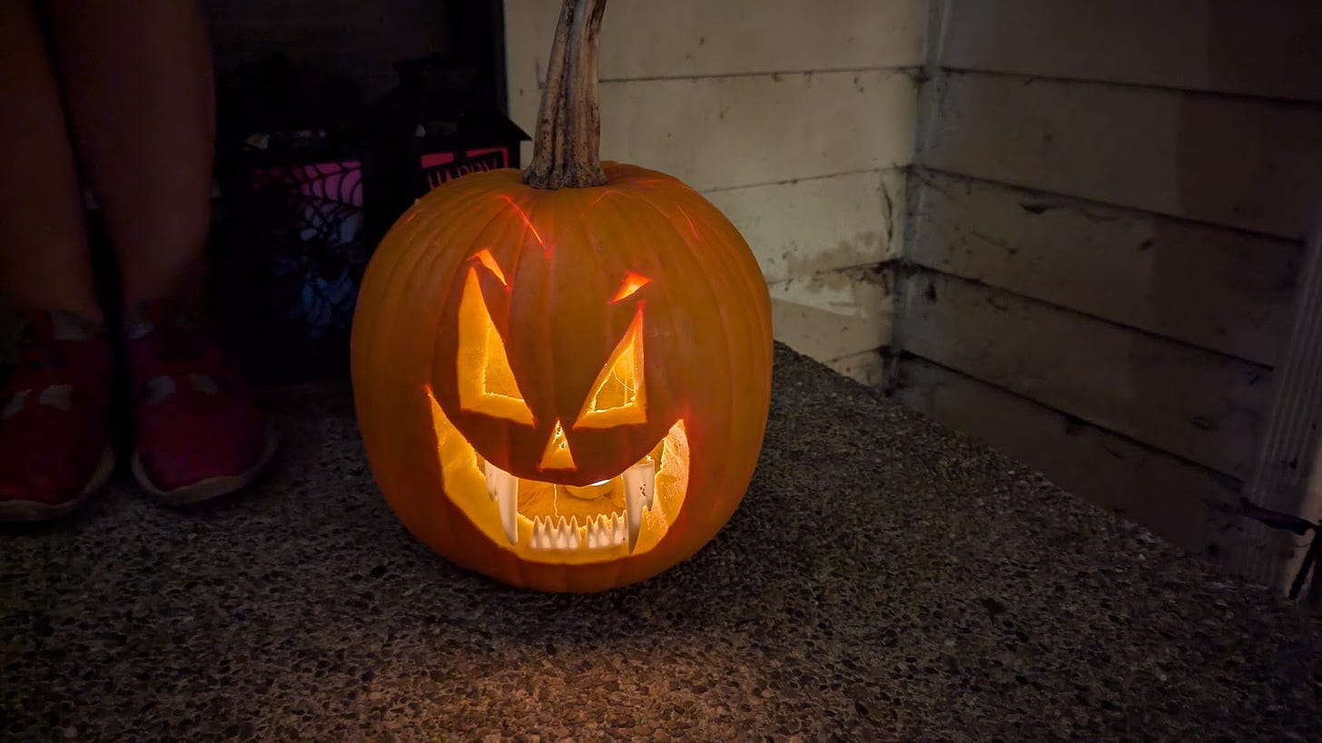 A carved pumpkin with sharp teeth lit from inside