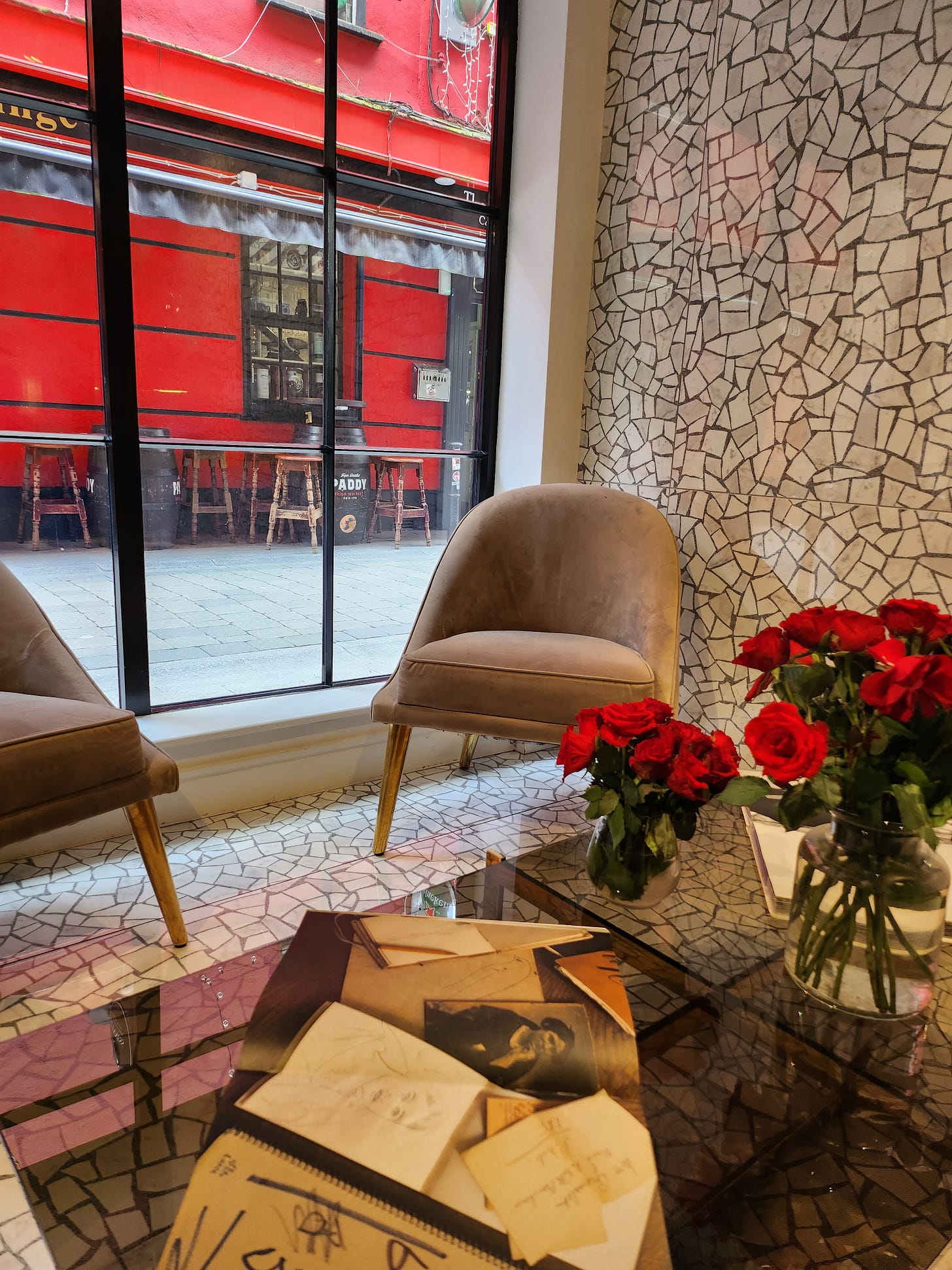 The view from inside The Hive. A table is filled with red roses and books, as the Bankers pub can be seen outside. 