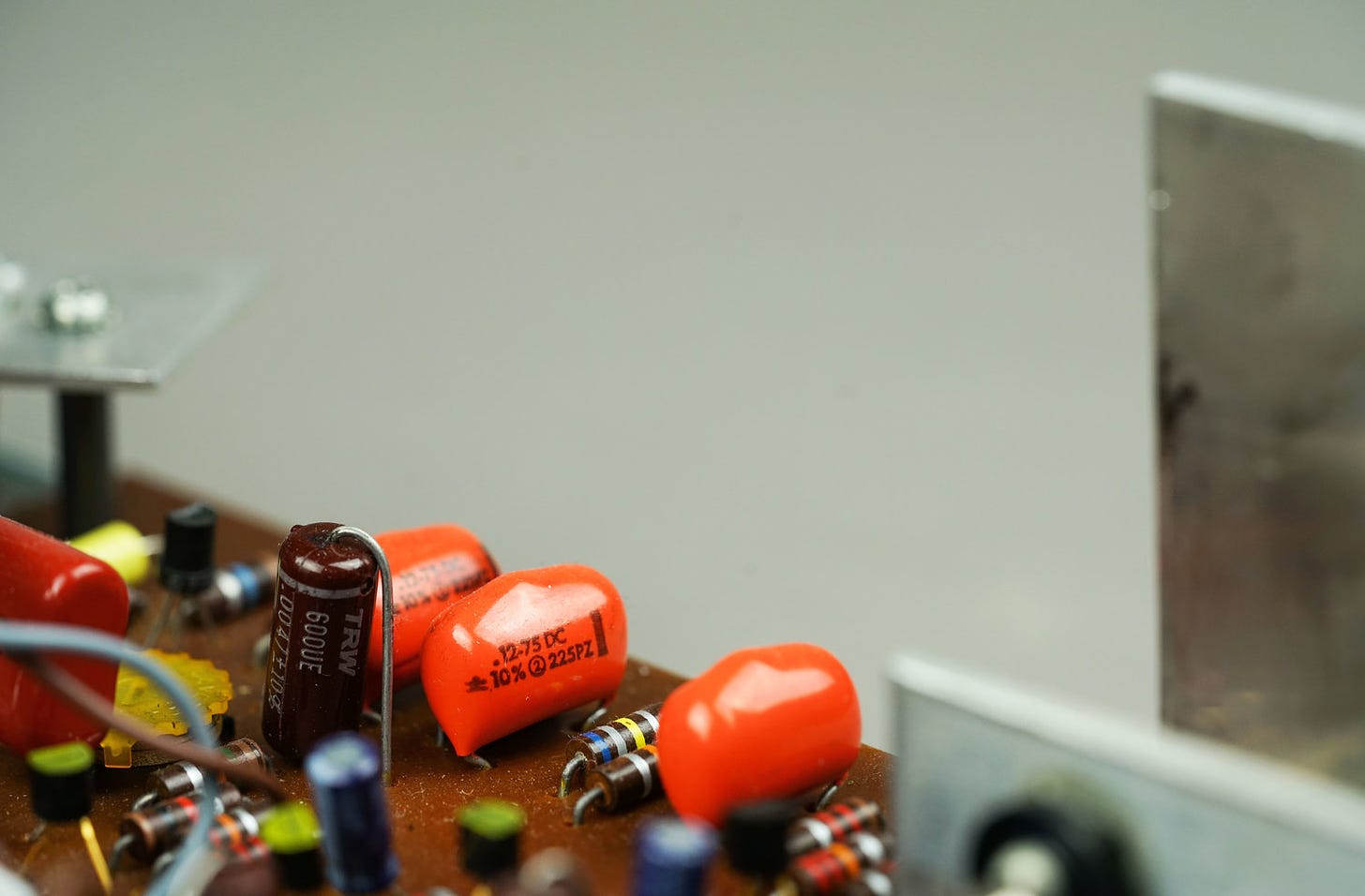 Closeup photo of three orange tremolo capacitors in a Wurlitzer 200 amplifier