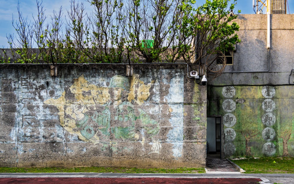 Political slogans flank a faded propaganda mural of a KMT soldier at the New Life Correction Center on Green Island, Taiwan