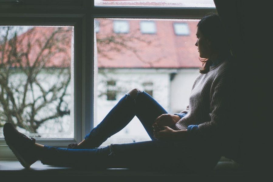 woman-sitting-in-windown-looking-out-depressed