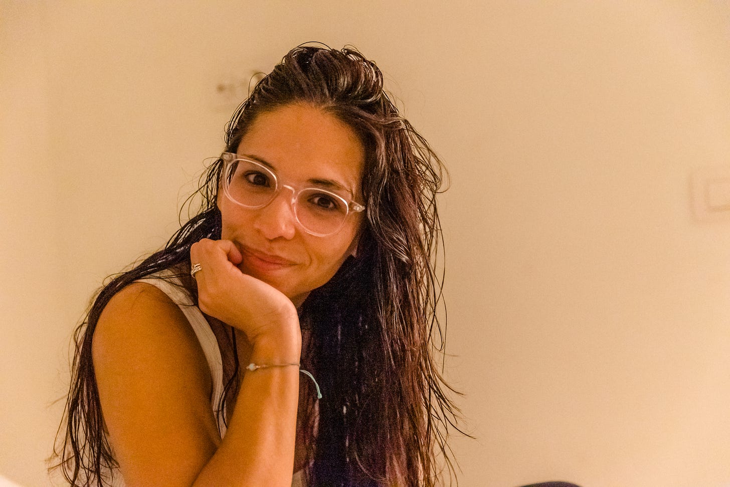 Photo of woman smiling to camera with her palm resting up against her chin