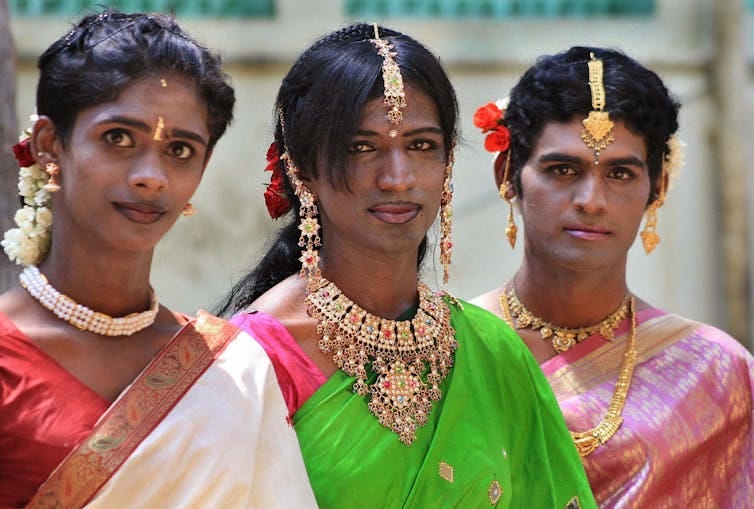 Three eunuchs in coloured saris with jewels.