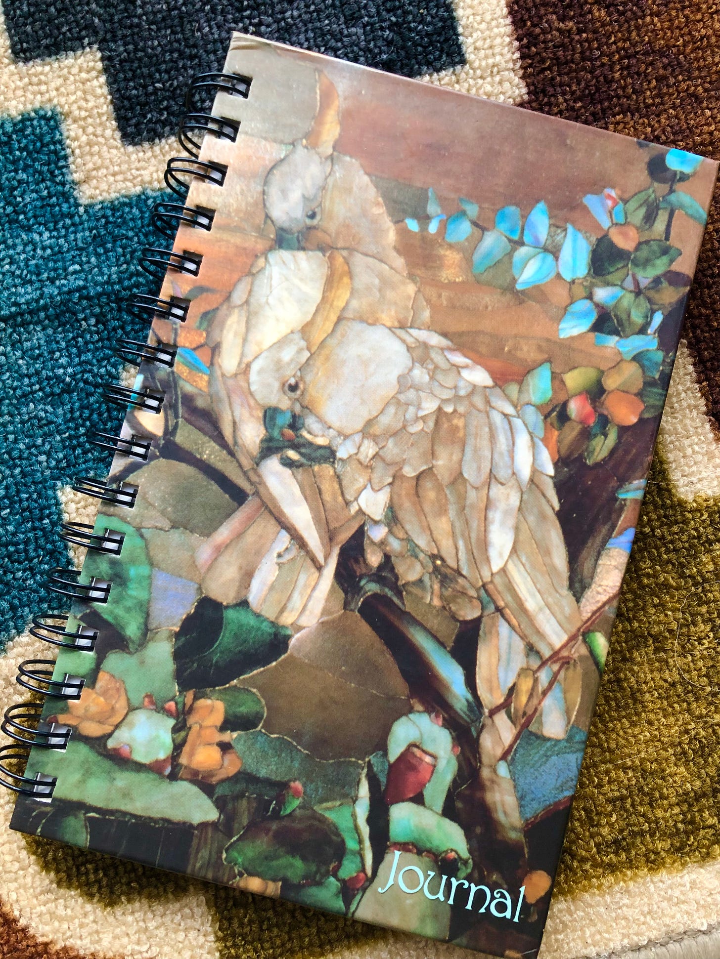 A journal's cover bears the image of two white love-birds rendered in stained glass.