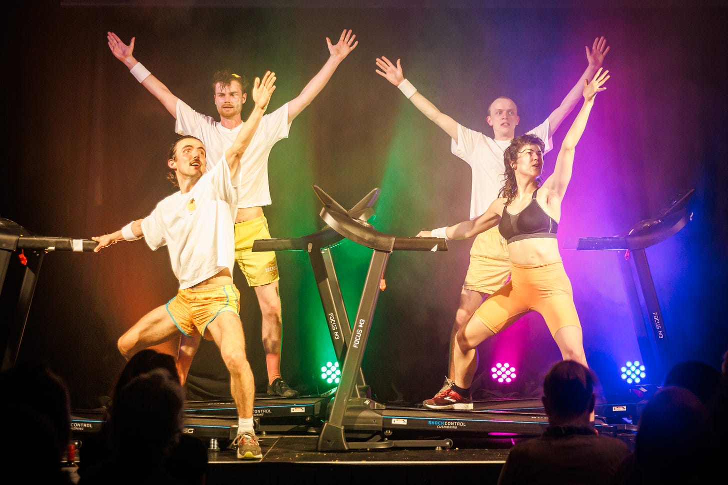 A photograph of Burnout Paradise showing four performers in sports gear making triumphant poses on treadmills