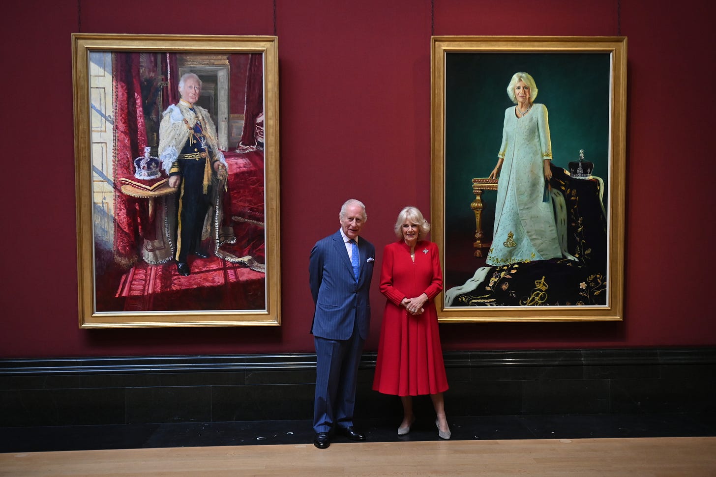 King Charles and Queen Camilla in front of portraits of themselves