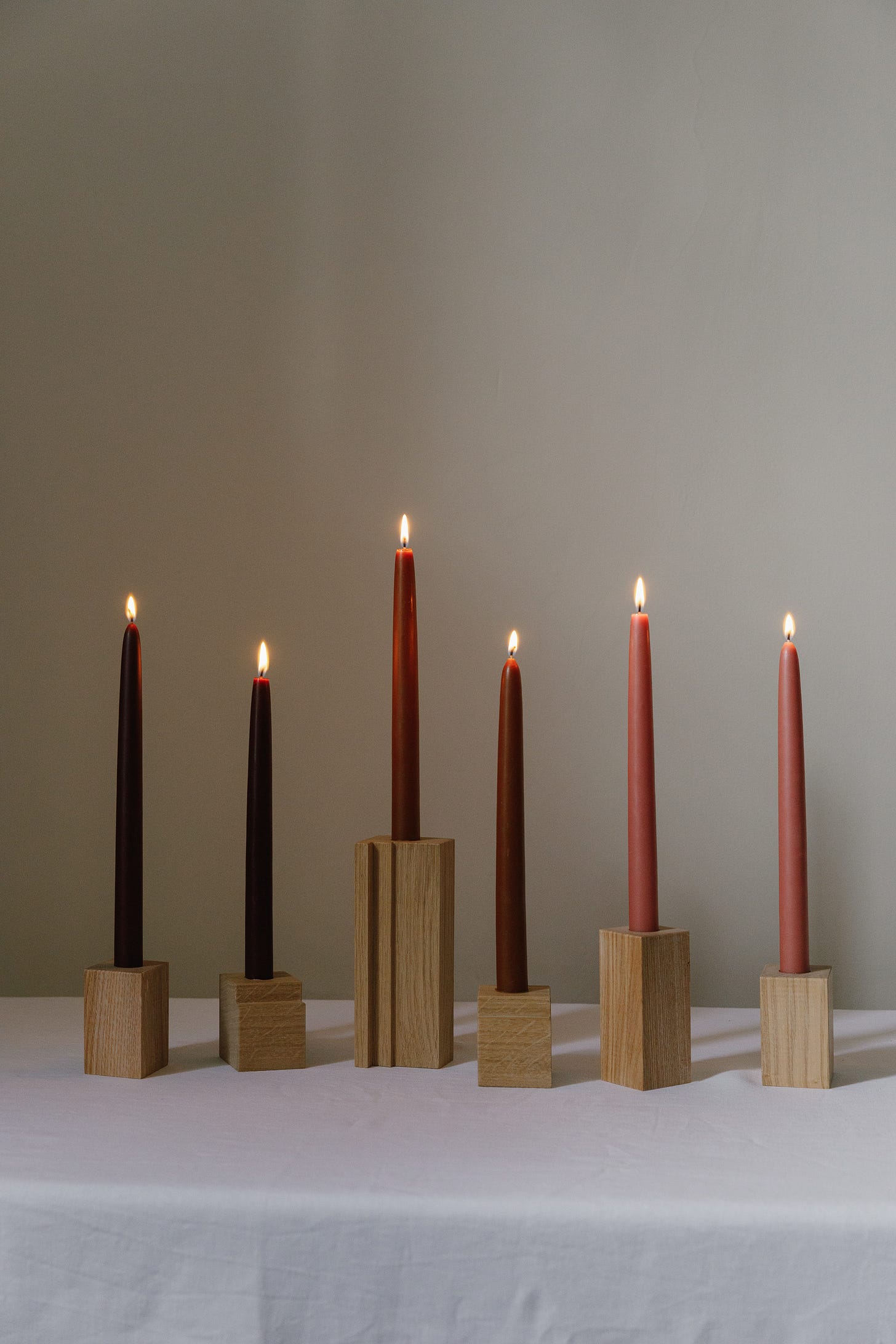 a tabletop with a tablecloth. a row of six lit dinner candles stood in wooden blocks