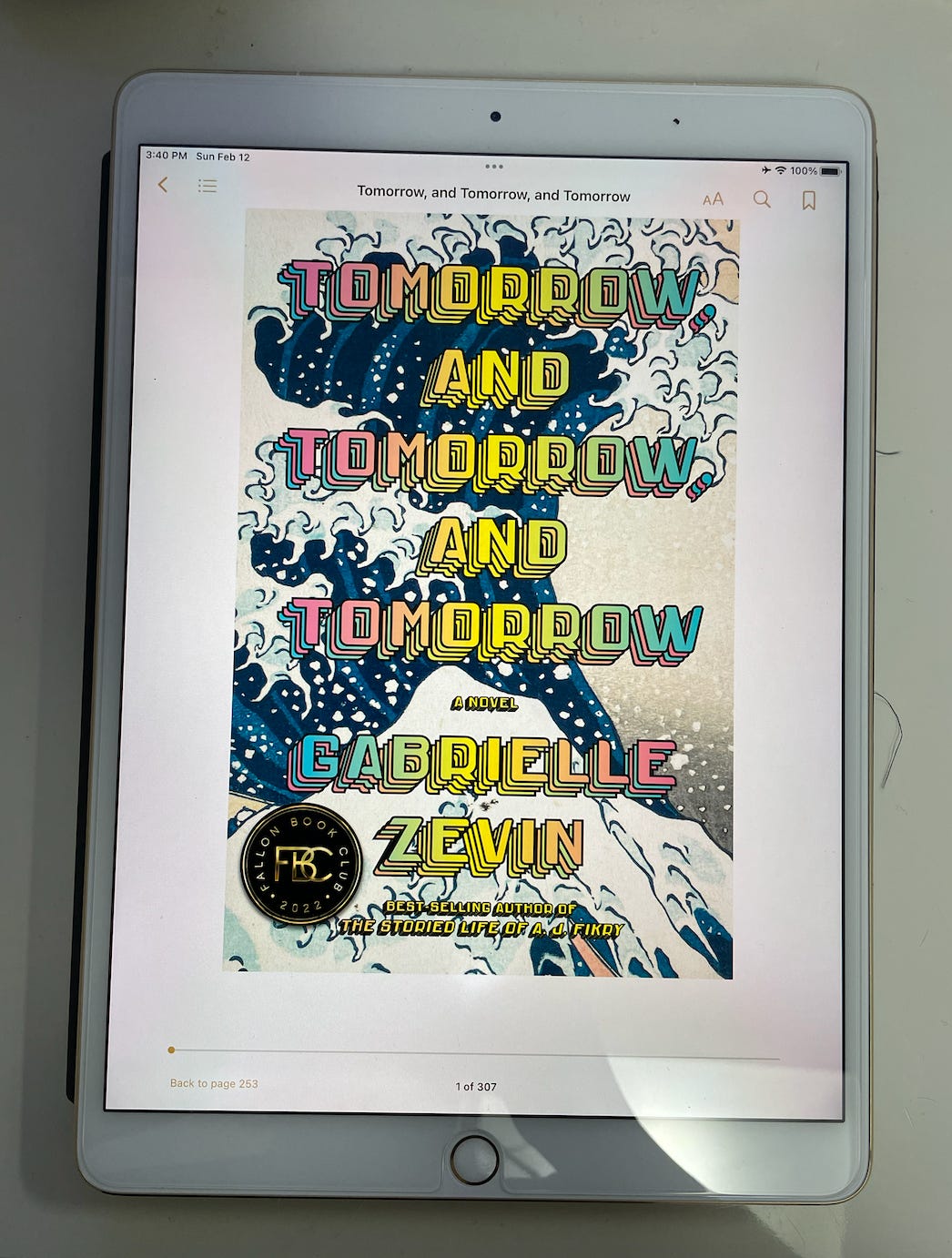 The book cover for Tomorrow, and Tomorrow, and Tomorrow by Gabrielle Zevin. The cover has a tidal wave in the style of The Great Wave off Kanagawa, and the text is written in retro video game font. The book is a Fallon Book Club 2022 pick.