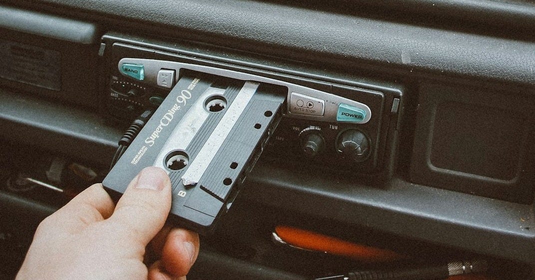 person inserting cassette tape on cassette player