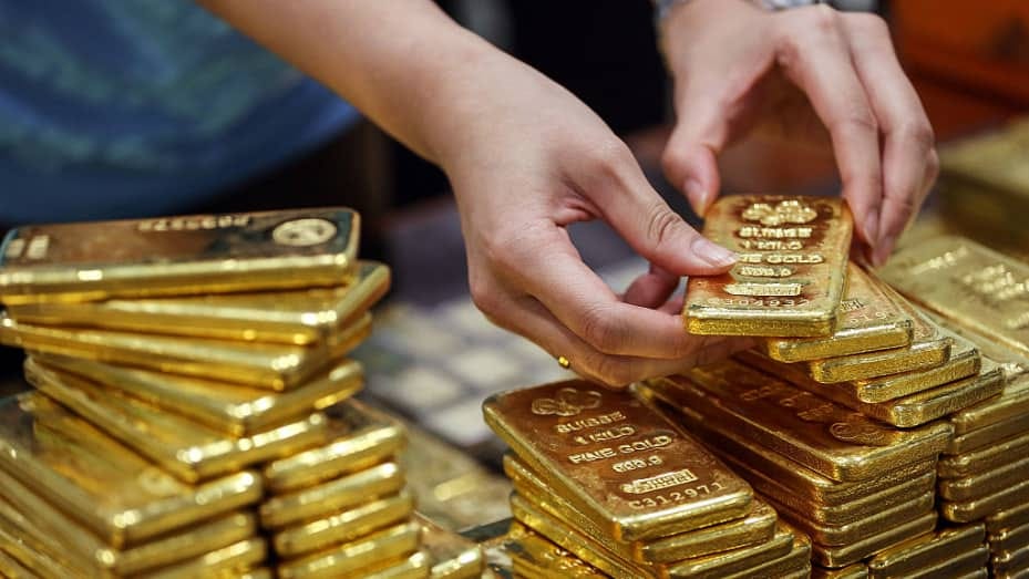 An employee arranges gold bars for a photograph at the YLG Bullion International headquarters in Bangkok, Thailand.