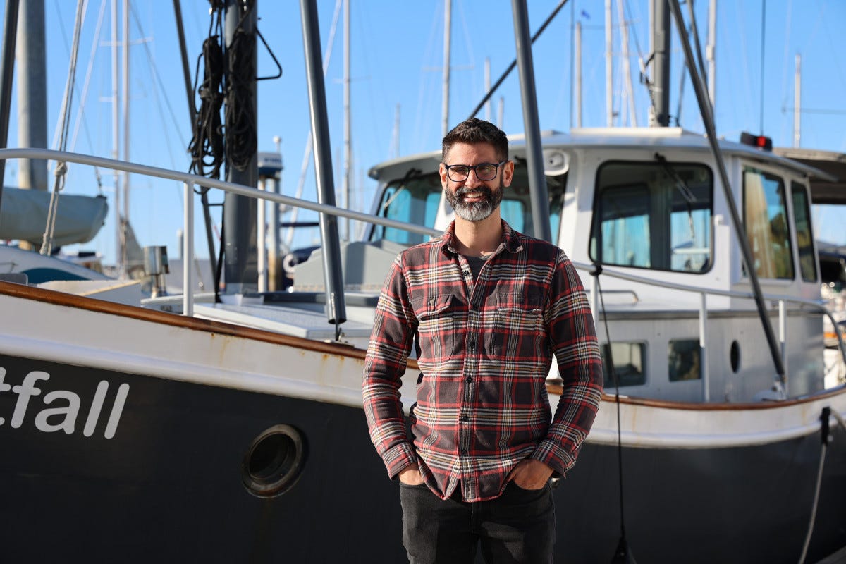 Andy Stewart, the younger half of the boat-owning duo, in front of Nightfall at her slip in the Ballard section of Seattle.