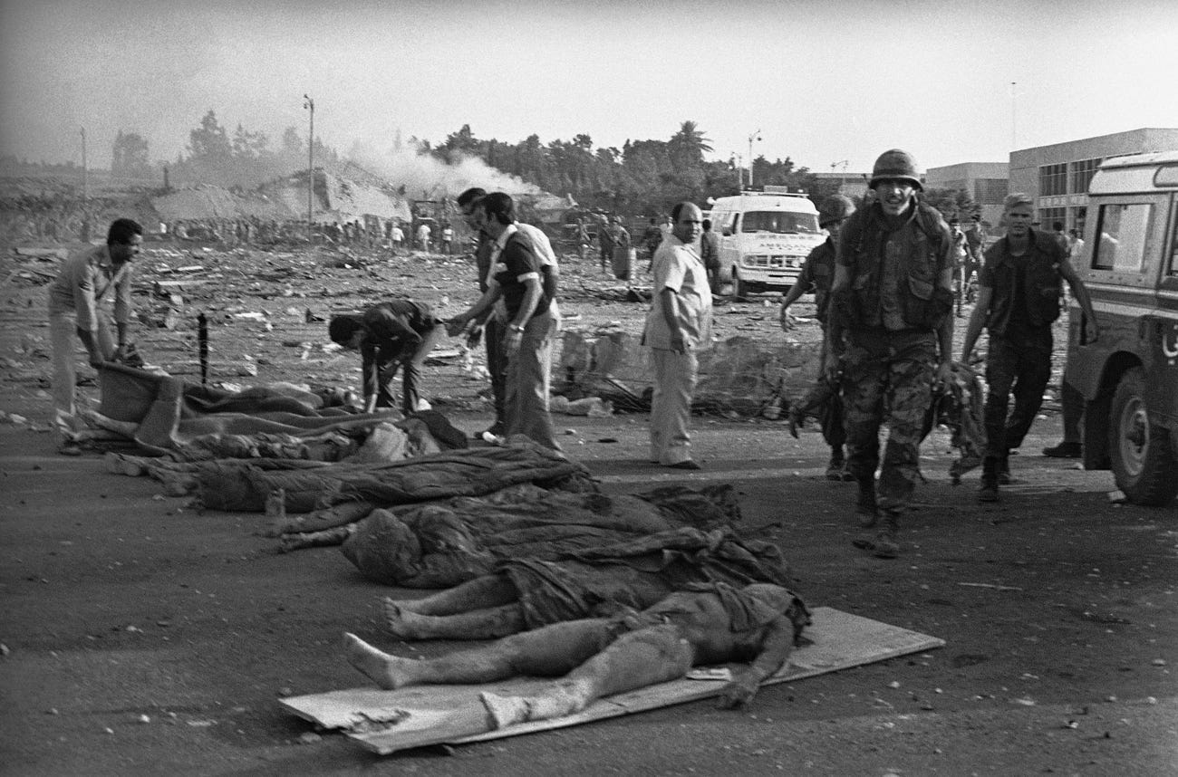 U.S. Marines carry their dead comrades away from the four-story command center that was destroyed in a bomb blast.