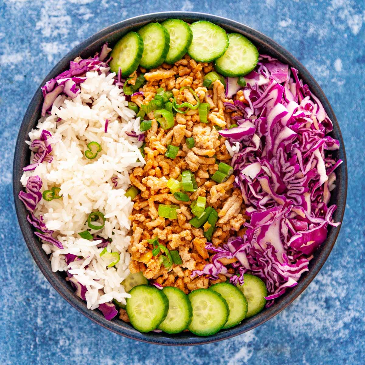 A bowl of white rice, ground chicken and veggies