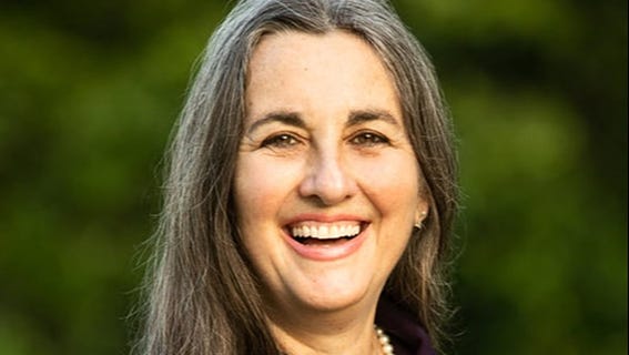 Author Janisse Ray. Adult female smiling outside with green background.